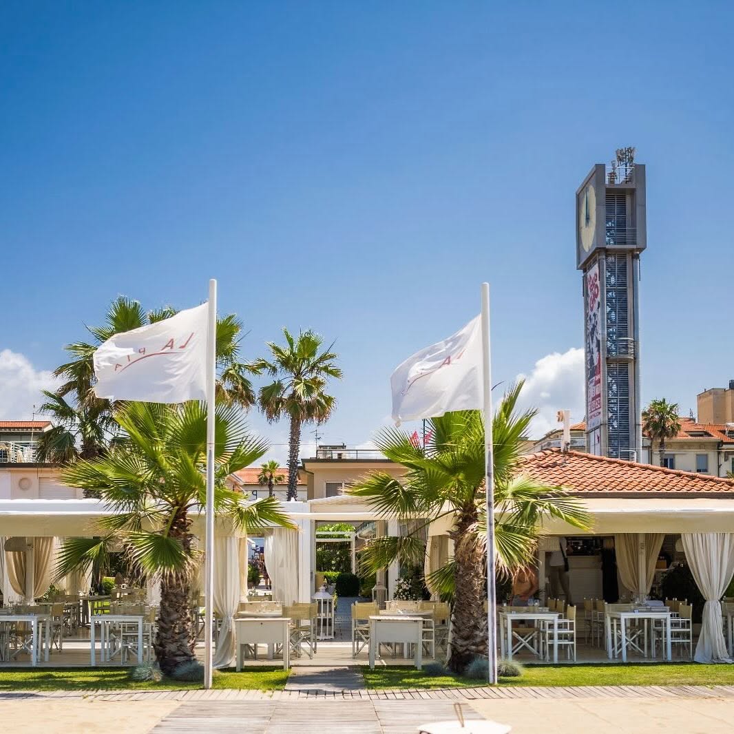Il ristorante La Pia visto dalla spiaggia di Viareggio, con bandiere bianche e palme
