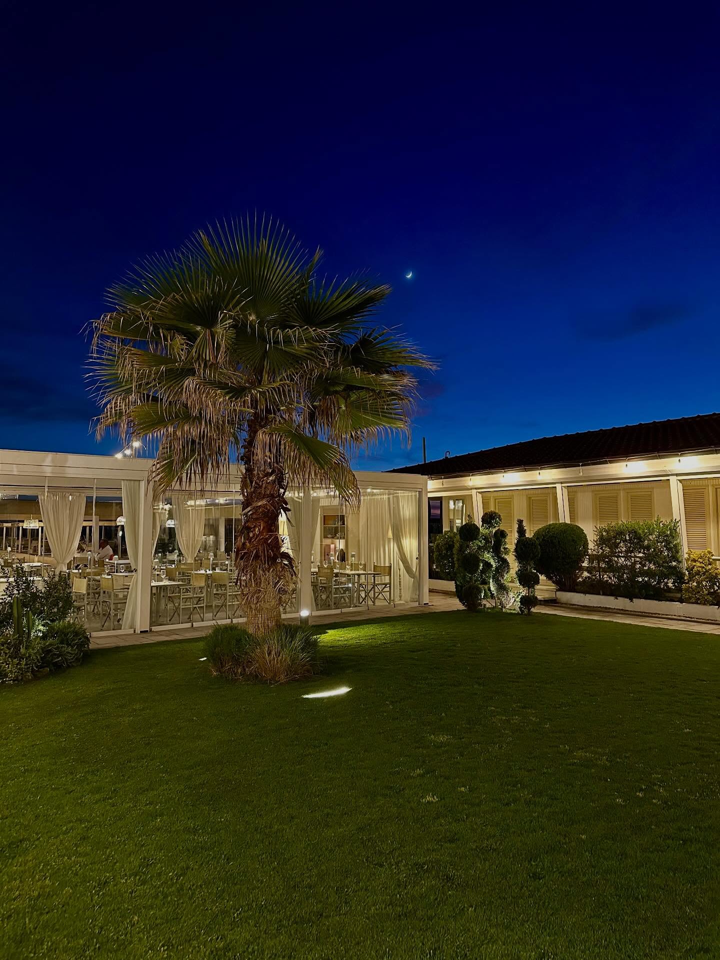 Giardino interno di La Pia la sera, con palma illuminata e veranda