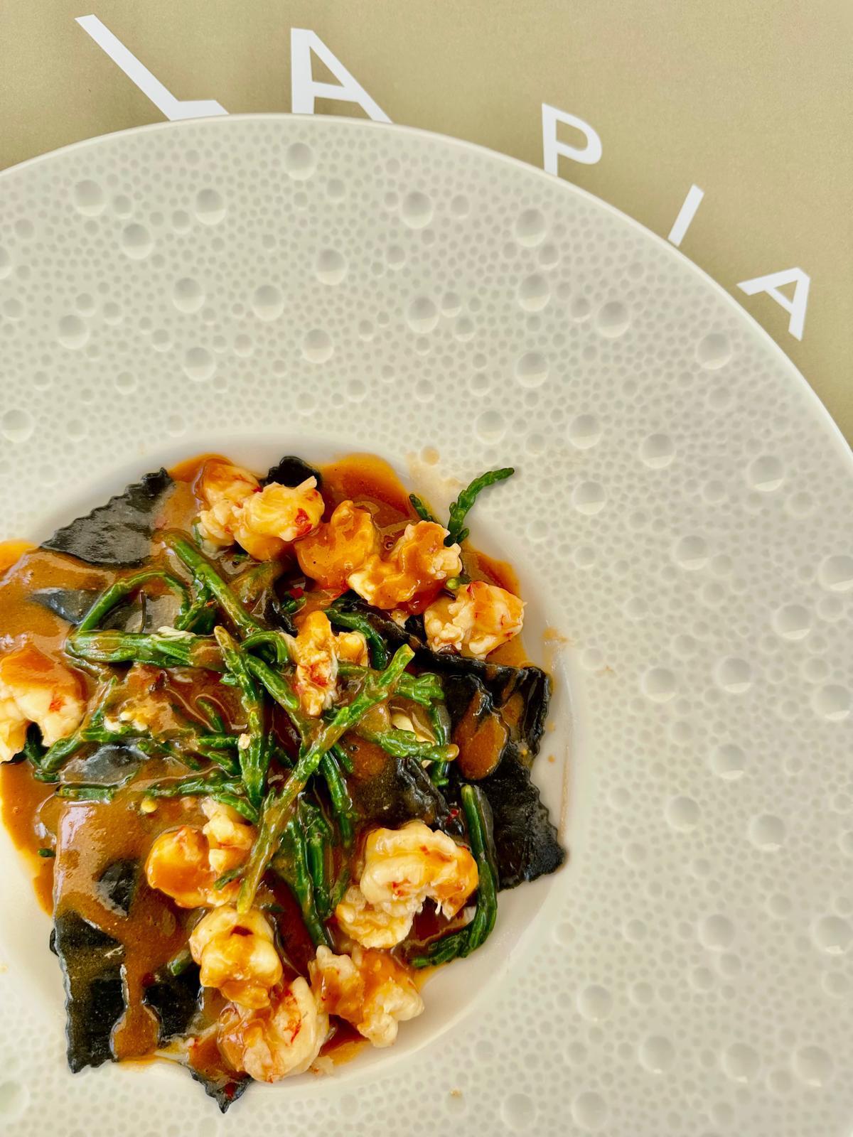 Raviolo al nero di seppia con gamberi e salicornia, nel piatto La Pia